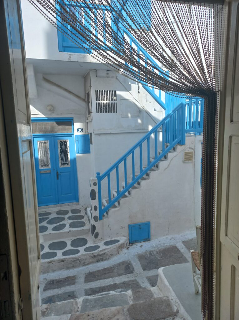 Cosa Vedere a Mykonos in un Giorno, veduta di un vicolo e casa con finestre blu