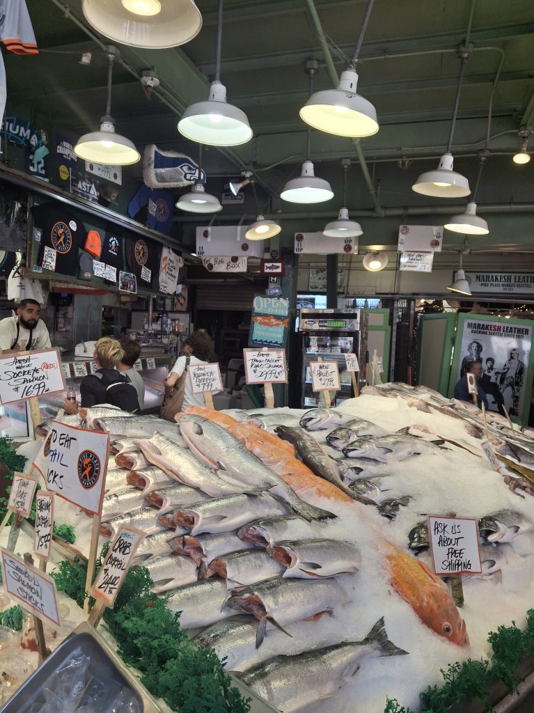  I pescivendoli del Pike Place Market dietro il bancone del pesce fresco, una famosa attrazione su cosa fare a Seattle prima di una crociera.